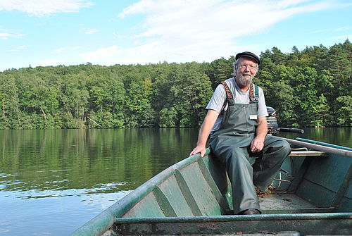 Fischer Weidner fährt an einem schönen Sommertagin seinem Kahn über den Hammersee, um seine Netze zu kontrollieren.