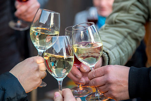 Verkostung beim alljährlichen Weinfest in Pillgram. Vier Menschen stoßen mit Weißwein an.